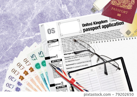 English form OS United Kingdom passport application from HM passport office lies on table with office items. UK passport paperwork English form OS United Kingdom passport application from HM passport office lies on table with office items. UK passport paperwork 79202650