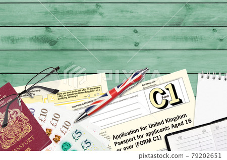 English form C1 Application for United Kingdom passport for applicants aged 16 or over lies on table with office items. UK passport paperwork 79202651