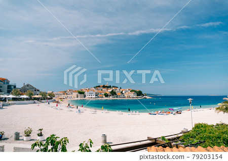Urban beach of Primosten town with people having a rest on the background of beautiful buildings and blue sky Urban beach of Primosten town with people having a rest on the background of beautiful buildings and blue sky 79203154