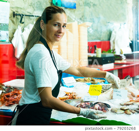 Saleswoman demonstrating seafoods assortment Saleswoman demonstrating seafoods assortment 79203268