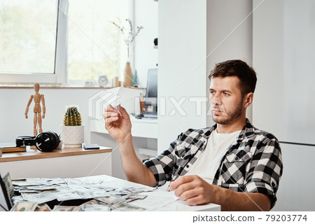 Man with laptop and dollar banknotes plays with paper plain 79203774
