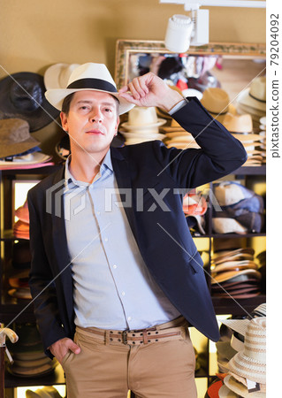 Portrait of guy try on sun hat at headwear store Portrait of guy try on sun hat at headwear store 79204092