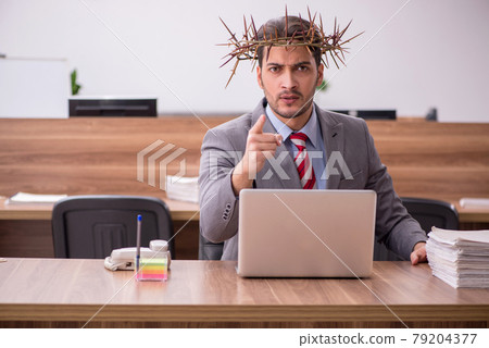 Young male employee wearing prickly wreath on head 79204377