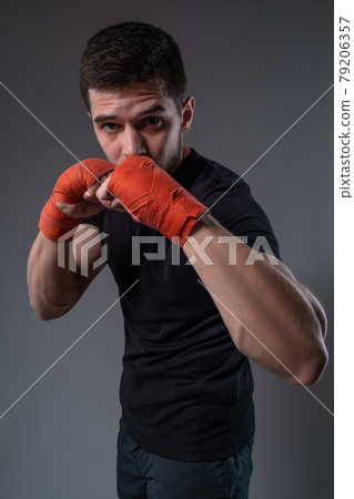 Concentrated fighter with wrist wraps standing in orthodox stance Concentrated fighter with wrist wraps standing in orthodox stance 79206357