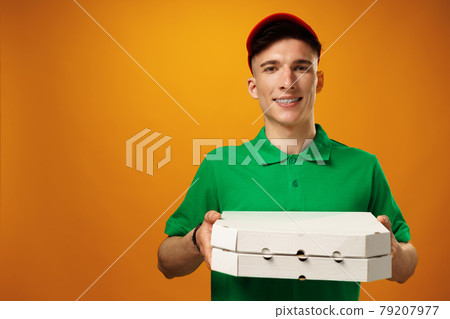 Happy young delivery man holding pizza box against yellow background 79207977