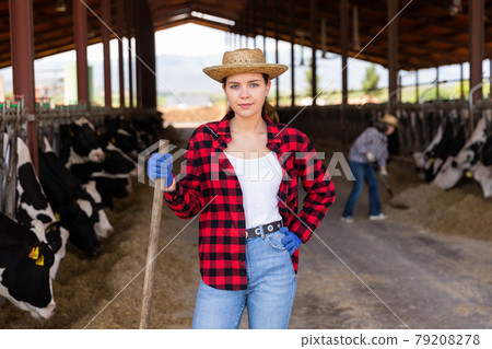 Smiling young woman cow breeder standing in cowshed Smiling young woman cow breeder standing in cowshed 79208278