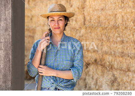 Woman posing at hay storage on farm 79208280