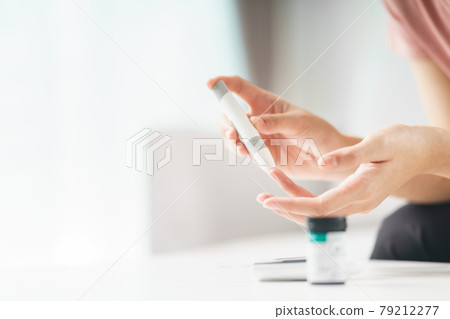 Asian woman using lancet on finger for checking blood sugar level by Glucose meter, Healthcare and Medical, diabetes, glycemia concept. 79212277