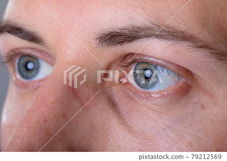Close up of blue eyes of caucasian businessman, isolated on grey background 79212569