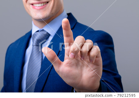 Midsection of caucasian businessman touching virtual interface, isolated on grey background 79212595