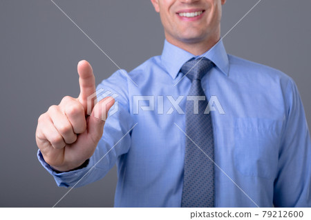 Midsection of caucasian businessman touching virtual interface, isolated on grey background 79212600