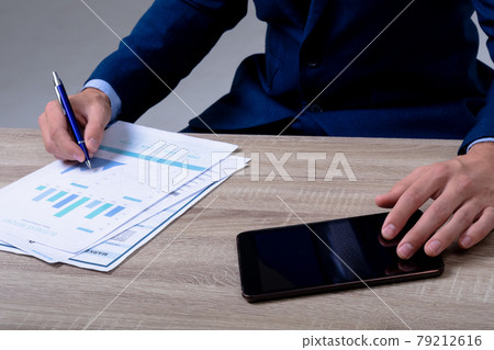 Midsection of caucasian businessman using smartphone and taking notes, isolated on grey background 79212616
