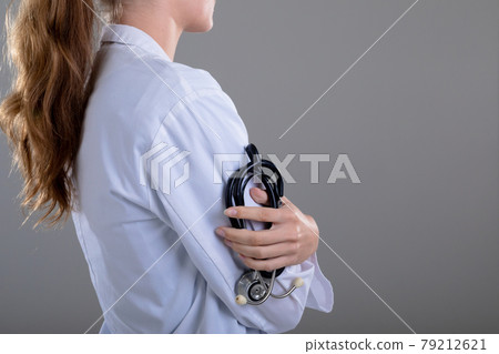 Midsection of caucasian female doctor holding stethoscope, isolated on grey background 79212621
