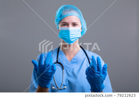 Portrait of caucasian female doctor wearing face mask and medical gloves 79212623