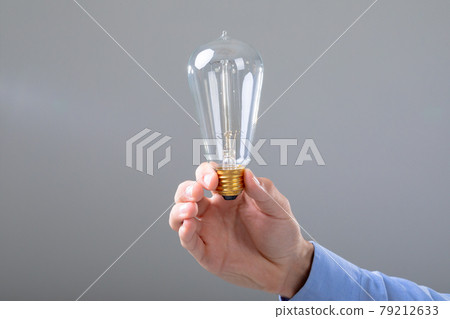 Midsection of caucasian businessman holding light bulb, isolated on grey background 79212633