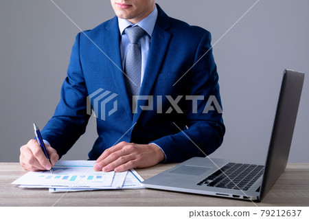 Midsection of caucasian businessman using laptop and taking notes, isolated on grey background 79212637