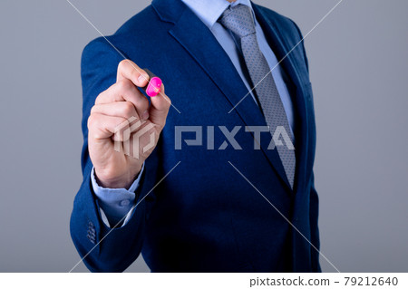 Midsection of caucasian businessman holding marker, isolated on grey background 79212640