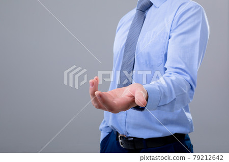 Midsection of caucasian businessman reaching his hand, isolated on grey background 79212642
