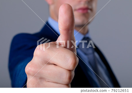 Midsection of caucasian businessman with thumb up, isolated on grey background 79212651