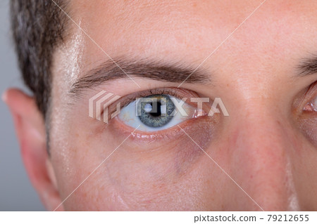 Close up of blue eye of caucasian businessman, isolated on grey background 79212655