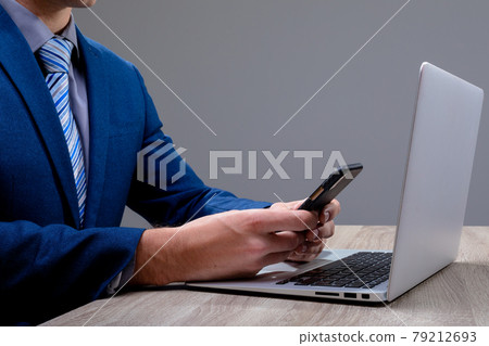 Midsection of caucasian businessman using smartphone and laptop, isolated on grey background 79212693