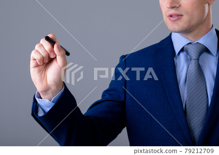 Midsection of caucasian businessman holding pen, isolated on grey background 79212709