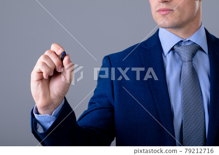 Midsection of caucasian businessman holding pen, isolated on grey background 79212716