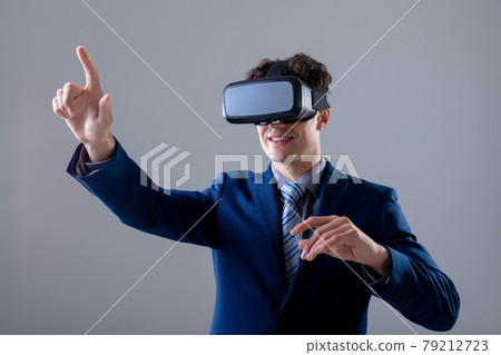 Caucasian businessman wearing vr headset touching virtual interface, isolated on grey background 79212723
