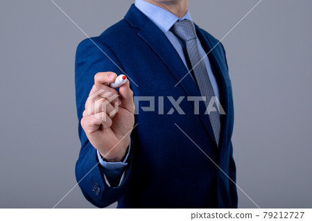 Midsection of caucasian businessman holding pen, isolated on grey background 79212727