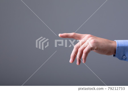 Midsection of caucasian businessman pointing with his finger, isolated on grey background 79212733