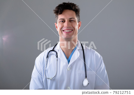 Portrait of caucasian male doctor looking at camera smiling, isolated on grey background 79212751