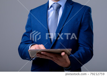 Midsection of caucasian businessman using digital tablet, isolated on grey background 79212759