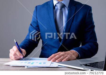 Midsection of caucasian businessman using laptop and taking notes, isolated on grey background 79212770