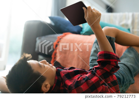 Asian boy using tablet with blank screen lying on floor at home 79212773
