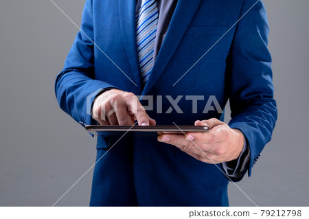 Midsection of caucasian businessman using tablet, isolated on grey background 79212798