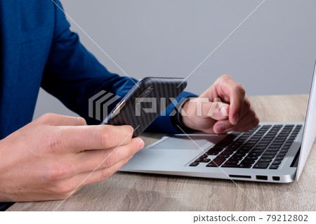 Midsection of caucasian businessman using smartphone and laptop, isolated on grey background 79212802