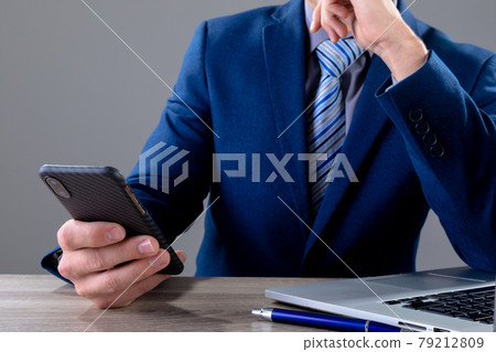 Midsection of caucasian businessman using smartphone, isolated on grey background 79212809