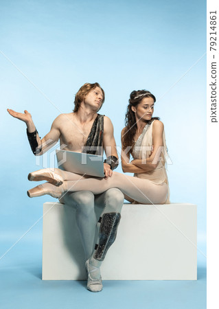 Tablet, laptop, digital. Young couple of ballet dancers in ancient Rome costums at blue studio. 79214861