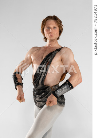 Spectacular man. Young male ballet dancer in ancient Rome costum posing at blue studio as historical image of Spartacus. 79214973