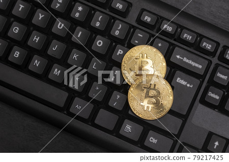 Two gold Bitcoins on computer keyboard close up. Electronic virtual money. Mining cryptocurrency concept. Two gold Bitcoins on computer keyboard close up. Electronic virtual money. Mining cryptocurrency concept. 79217425