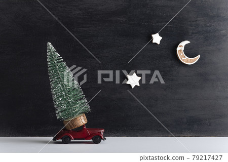 Small tree on model car, black background. Round-the-clock delivery for the new year 79217427