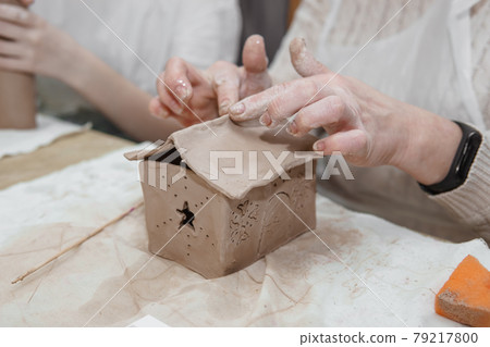 Women's hands knead clay, drawing elements of the product. Production of ceramic products at the master class on ceramics. 79217800