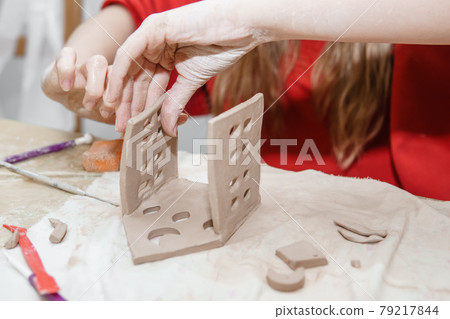 Women's hands knead clay, drawing elements of the product. Production of ceramic products at the master class on ceramics. 79217844