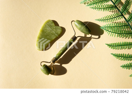 Jade Gua sha scraper and facial massager on beige background. Jade Gua sha scraper and facial massager on beige background. 79218042