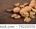 whole and peeled dried walnuts on wooden backbground 79220356