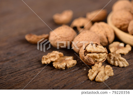 whole and peeled dried walnuts on wooden backbground 79220356