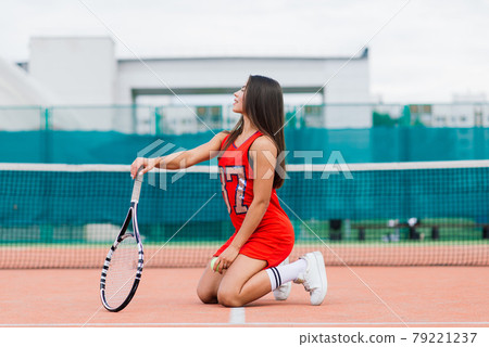 Beautiful female tennis player on tennis court. Red dress. Beautiful female tennis player on tennis court. Red dress. 79221237