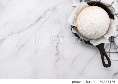 Fresh raw homemade yeast dough resting in cast iron skillet on marble table flat lay.. Fresh raw homemade yeast dough resting in cast iron skillet on marble table flat lay.. 79221476