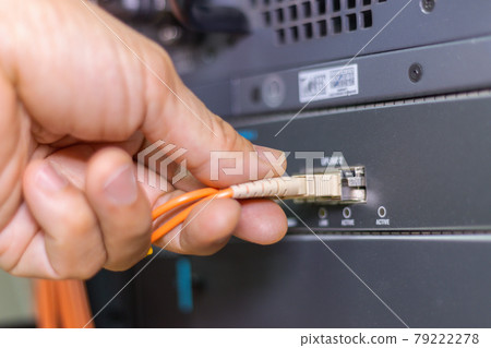 Hand of a man holding The network fiber optic cables to connect the port of a switch to connect internet network, concept Communication technology Hand of a man holding The network fiber optic cables to connect the port of a switch to connect internet network, concept Communication technology 79222278