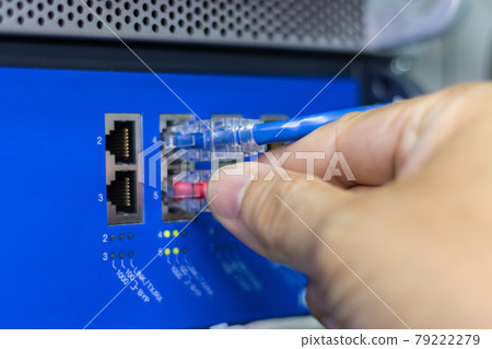 Hand of a man holding The network cables to connect the port of a switch to connect internet network, concept Communication technology Hand of a man holding The network cables to connect the port of a switch to connect internet network, concept Communication technology 79222279